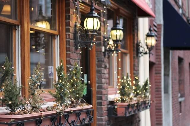 Storefront windows decorated with greenery and holiday lights