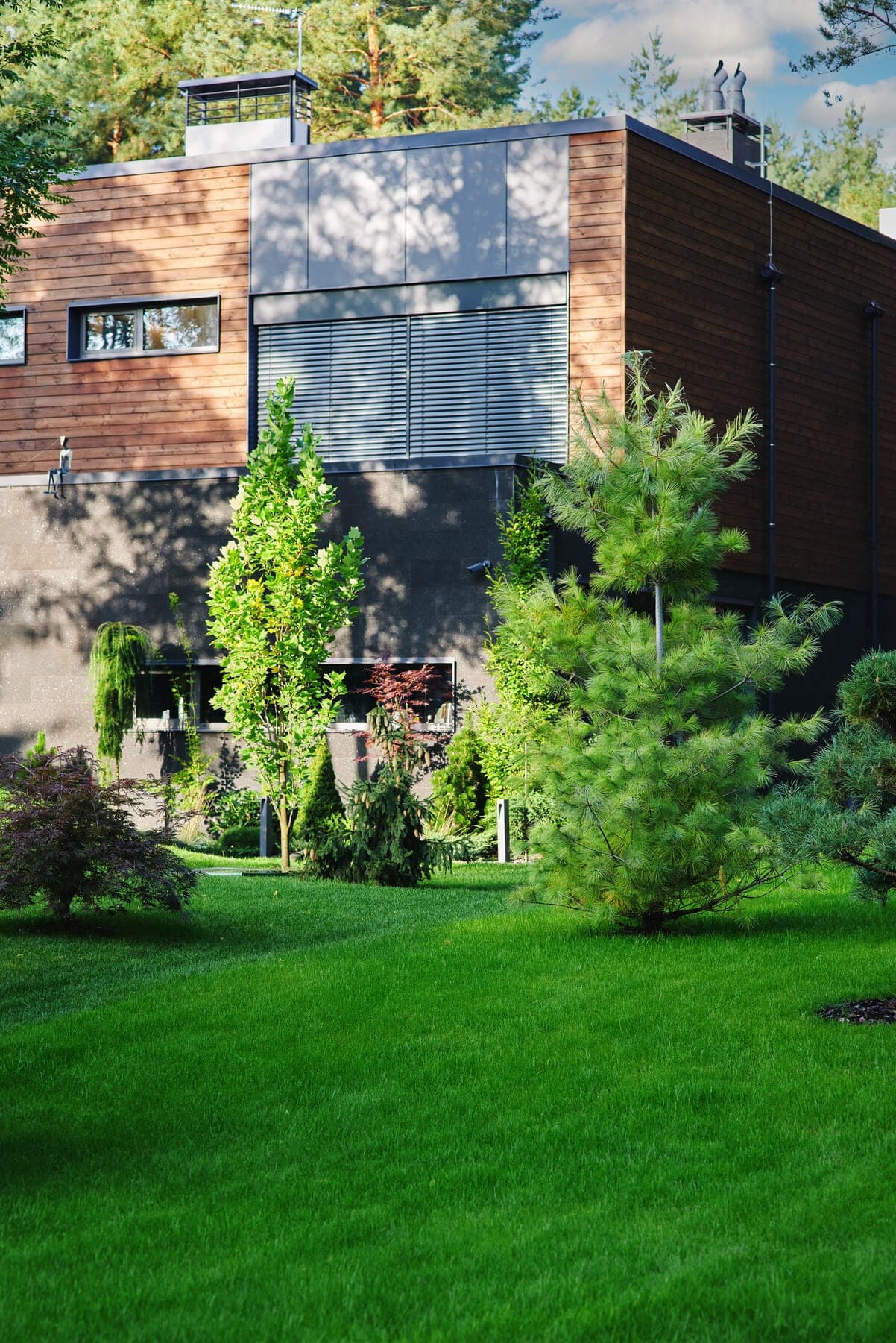 Home bordered by a lawn, trees and garden plants