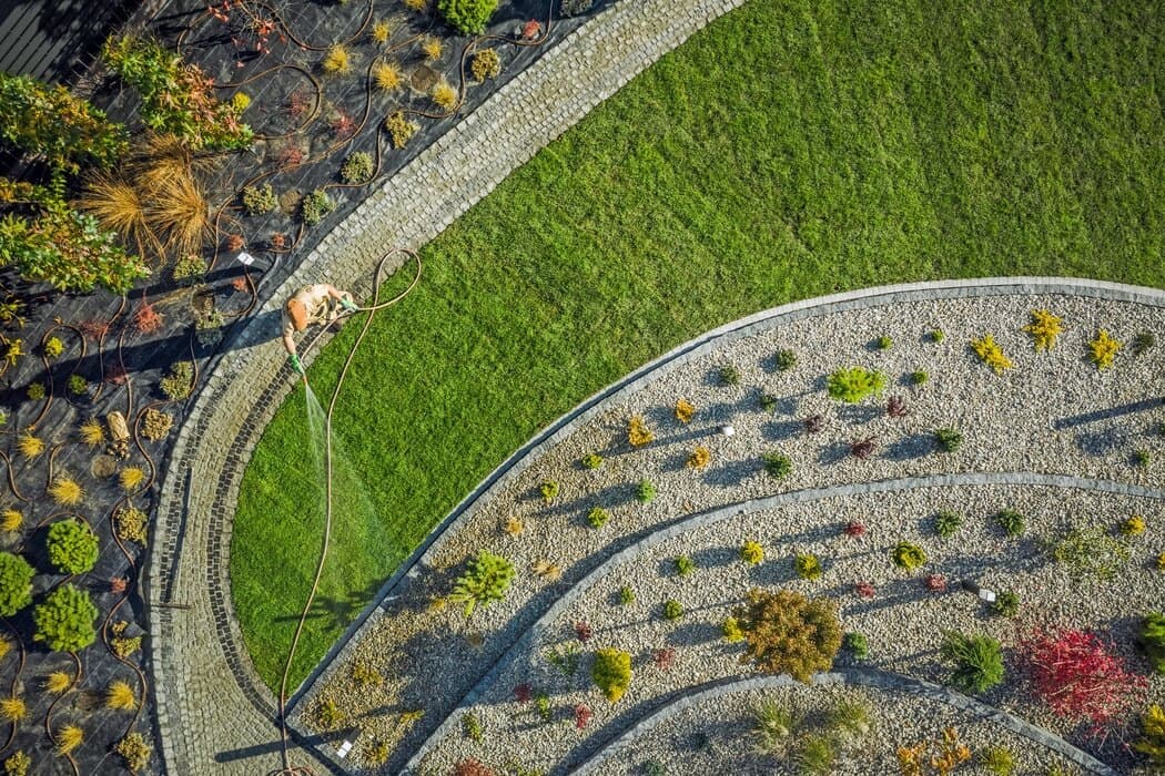 Curved garden beds bordering a strip of lawn